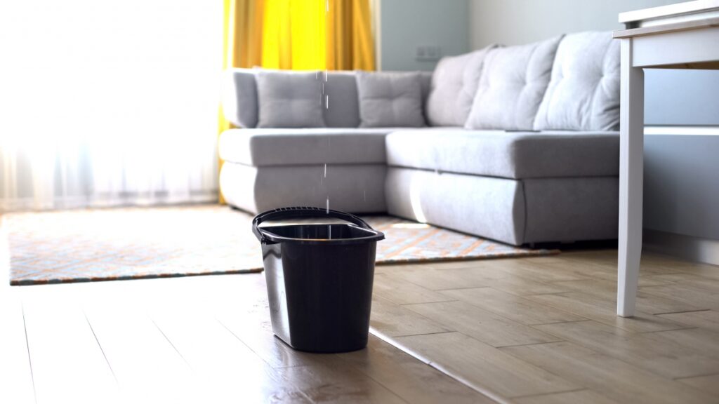 Water droplets leaking in bucket from ceiling, damaged roof, house renovation,
